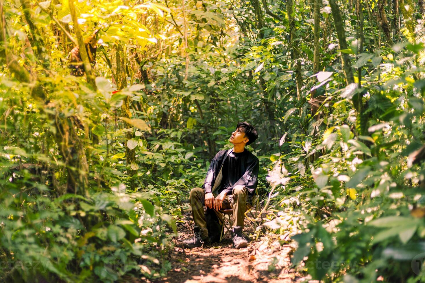 Man Resting in the Wilderness, Immersed in the Beauty of Nature. Calm and Pristine Mountain Forest Landscape. photo