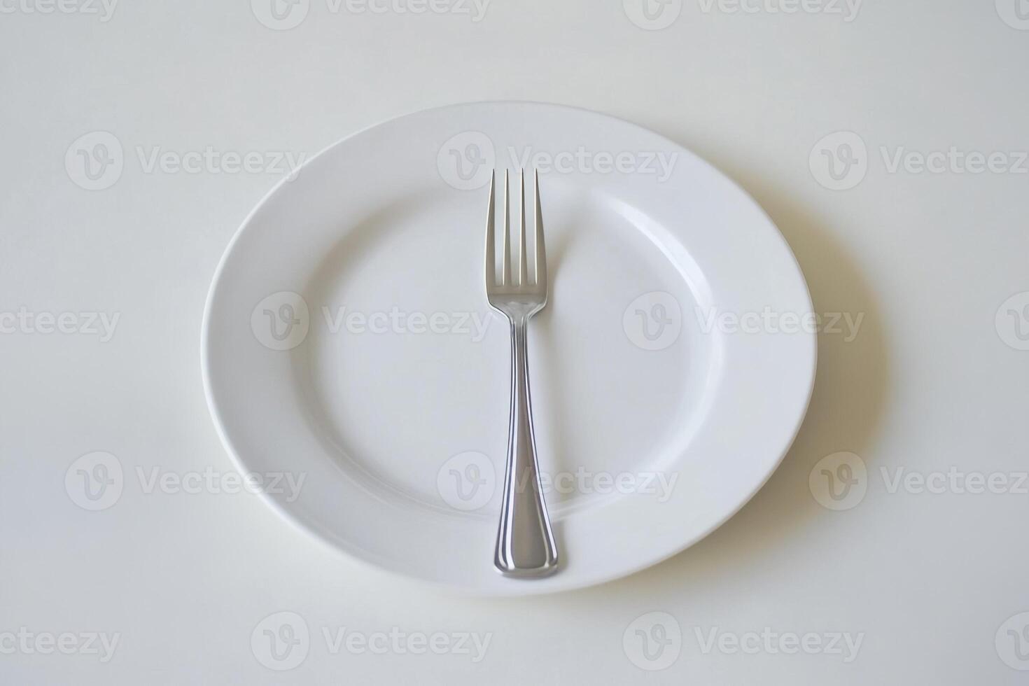 A single fork rests on a white plate, symbolizing emptiness or a fresh start. photo