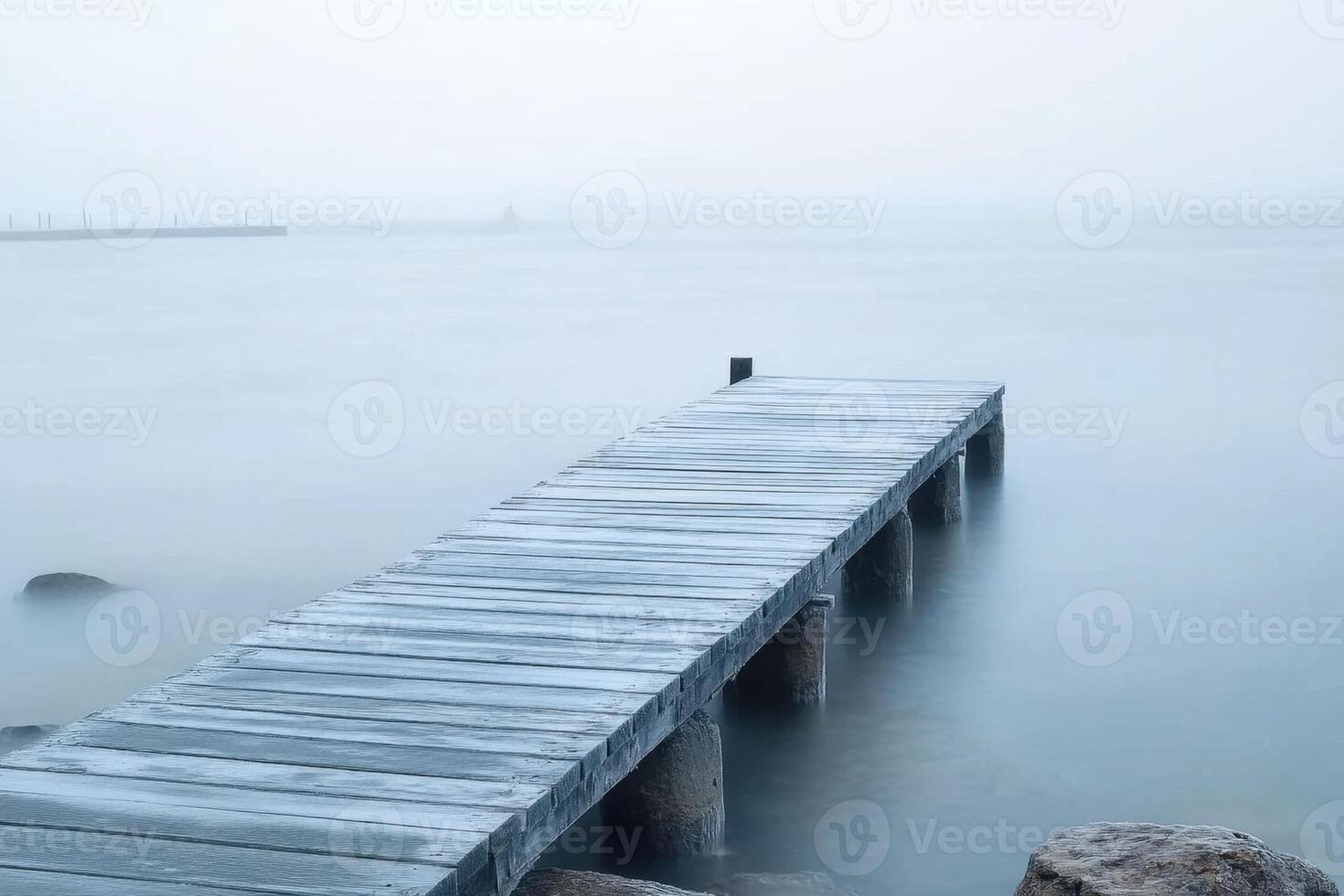 A wooden pier extends into a foggy lake. photo