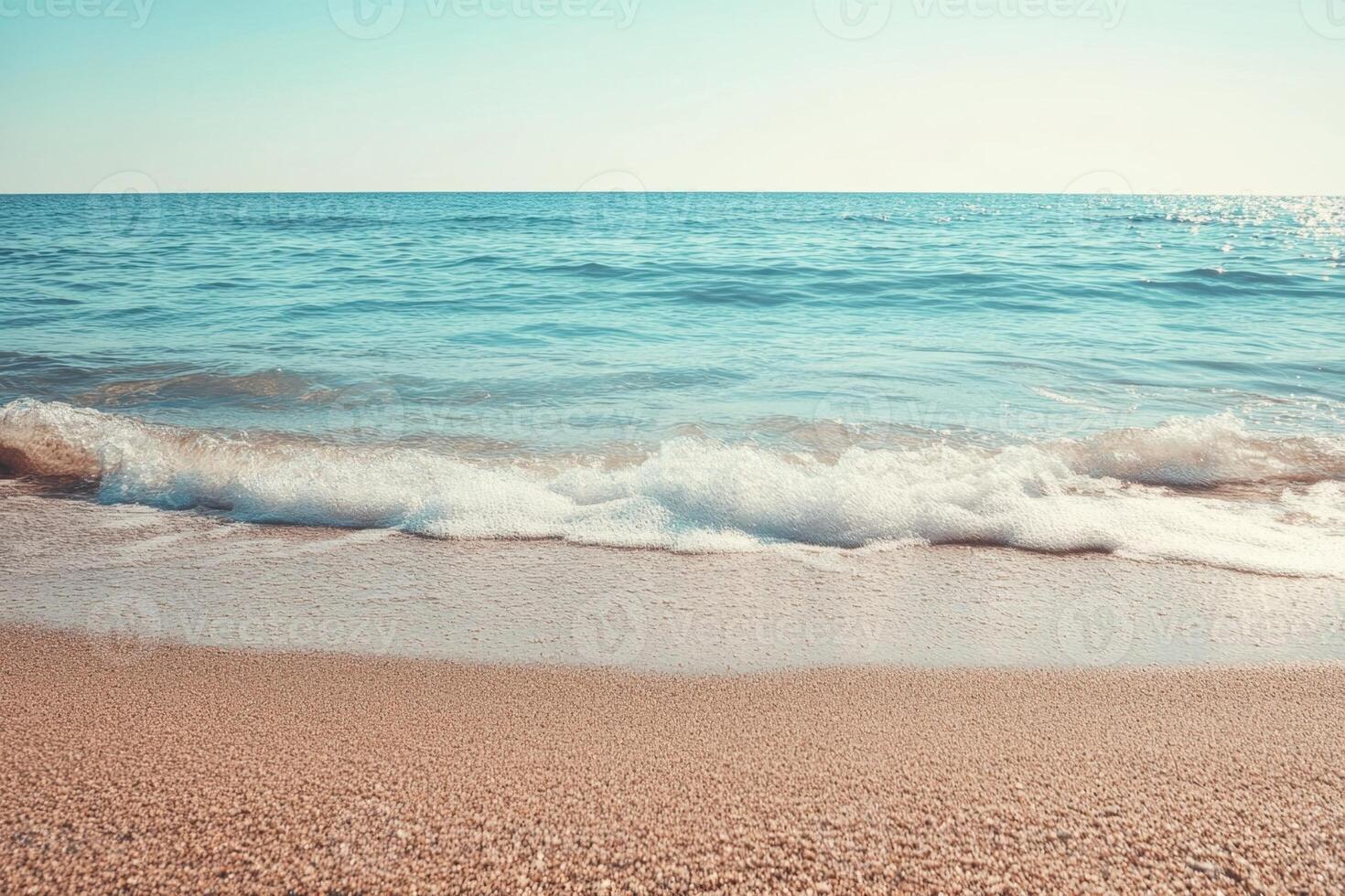 Gentle waves lap at the shore of a sandy beach. photo