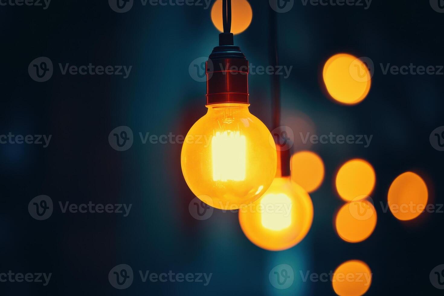 A single glowing light bulb hanging in front of a dark background with other out-of-focus light bulbs behind it. photo