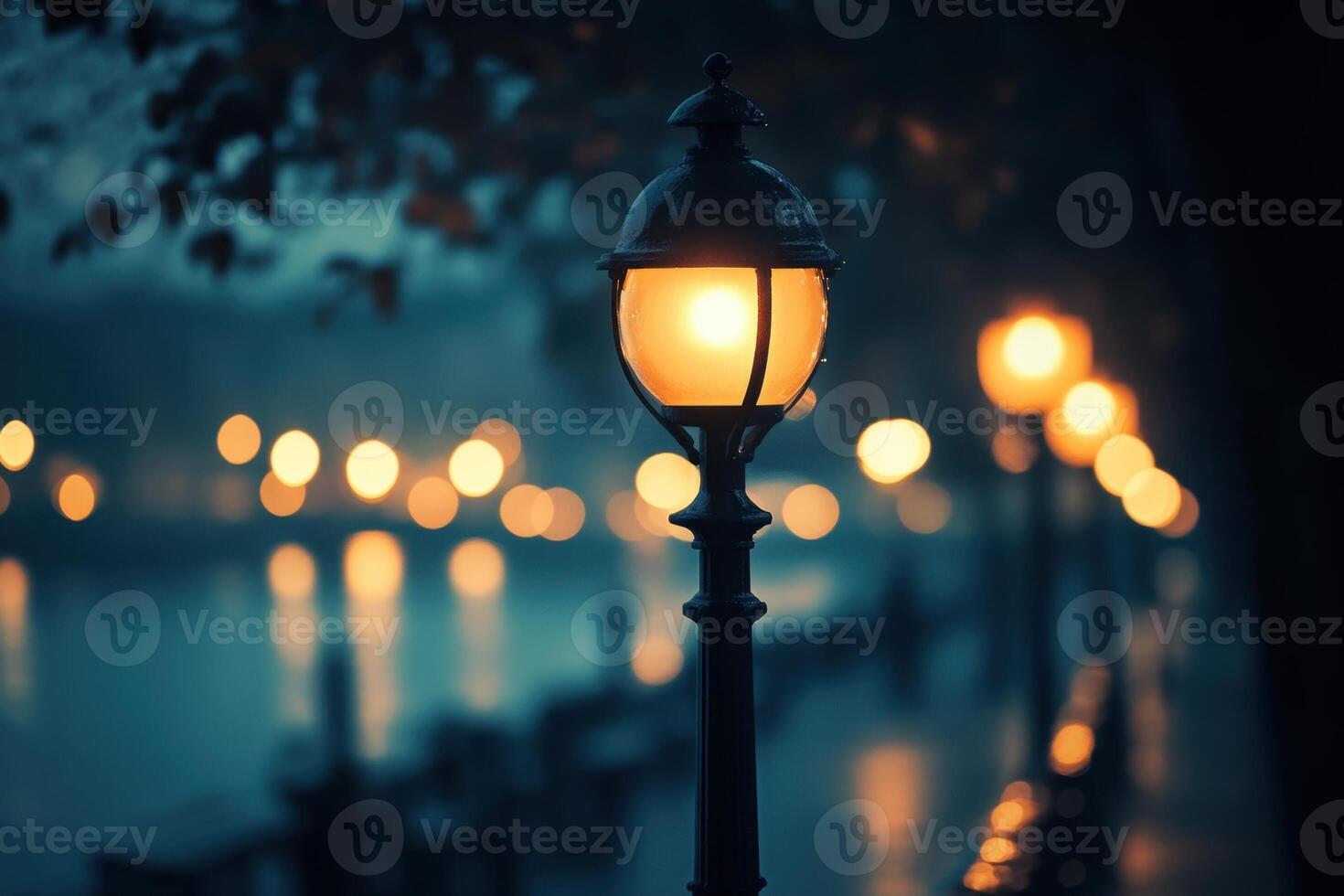 A single street lamp illuminates a foggy night scene with a line of other lights in the background. photo