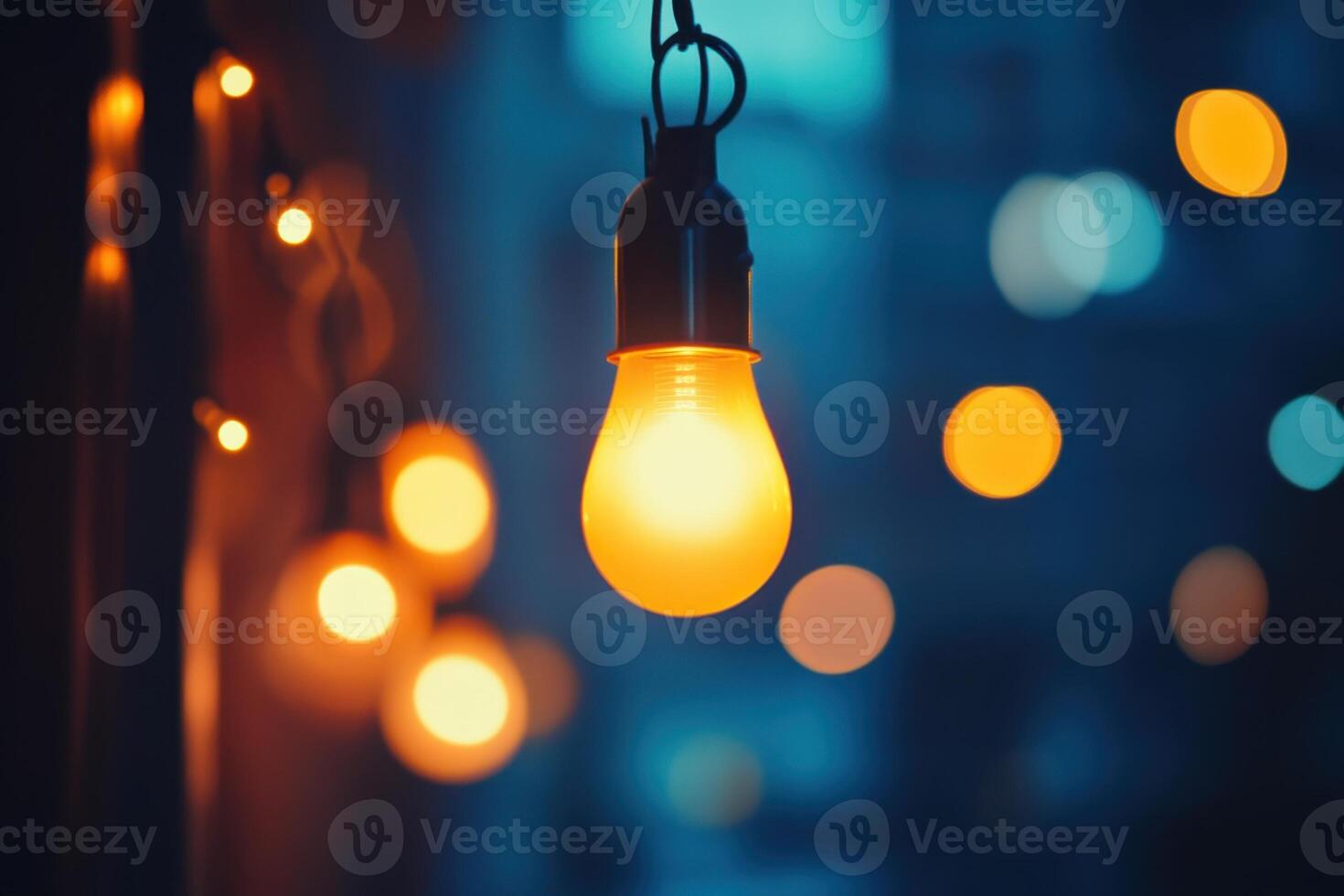 A single lightbulb hangs from a string of lights, glowing brightly against a blurry background of bokeh. photo