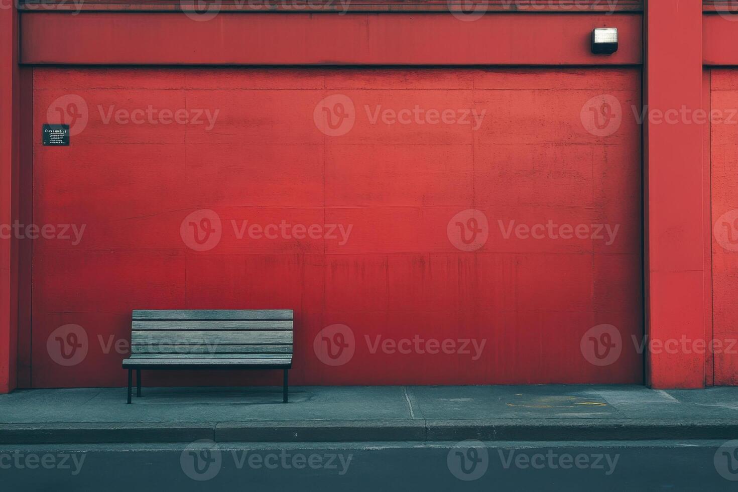 A lone bench sits in front of a bright red wall. photo