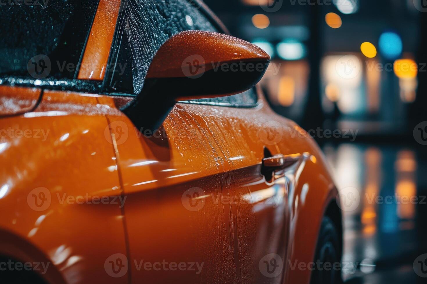 Close-up of an orange car getting washed, with water droplets and soap suds on the side. photo