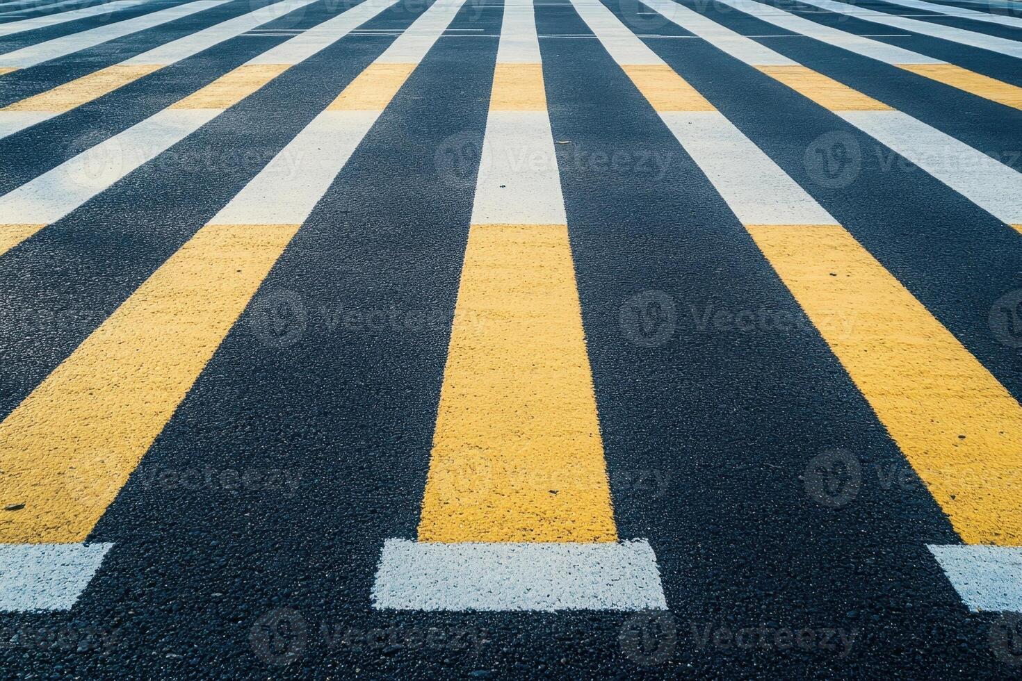 Yellow and white crosswalk stripes on a black asphalt road. photo