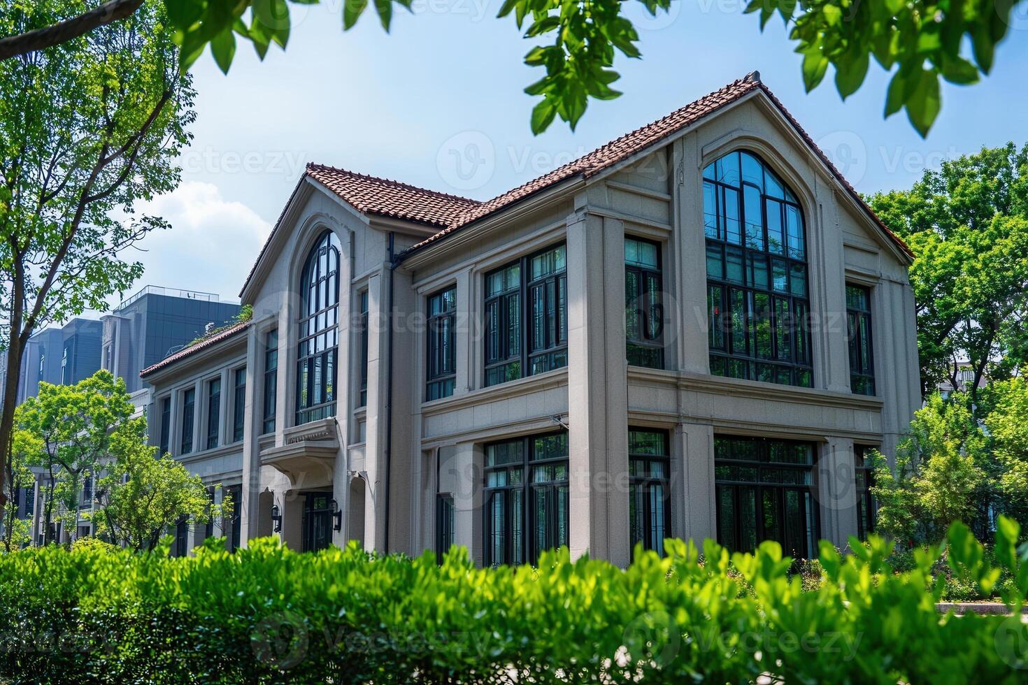 A modern, two-story house with large windows, surrounded by lush greenery. photo