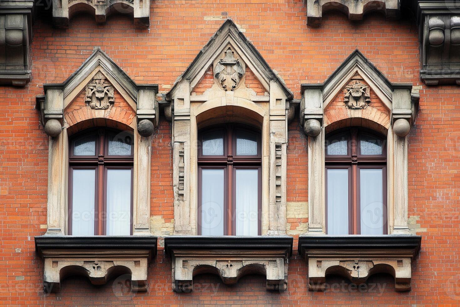 Three arched windows with ornate trim on a brick building. photo