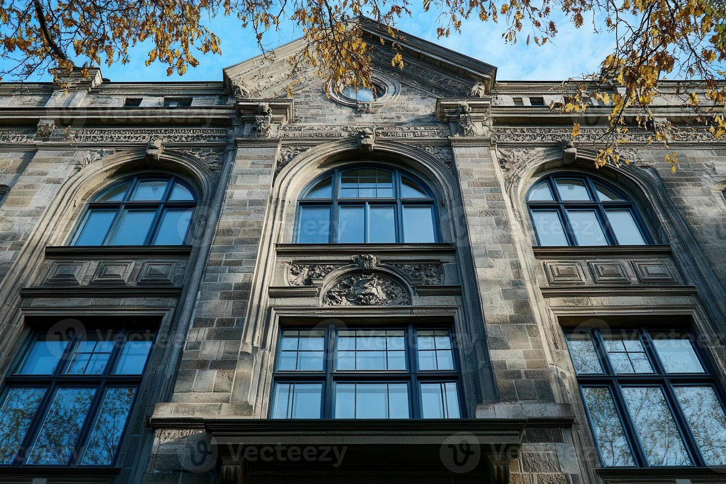 Stone facade of a historic building with arched windows and ornate details. photo