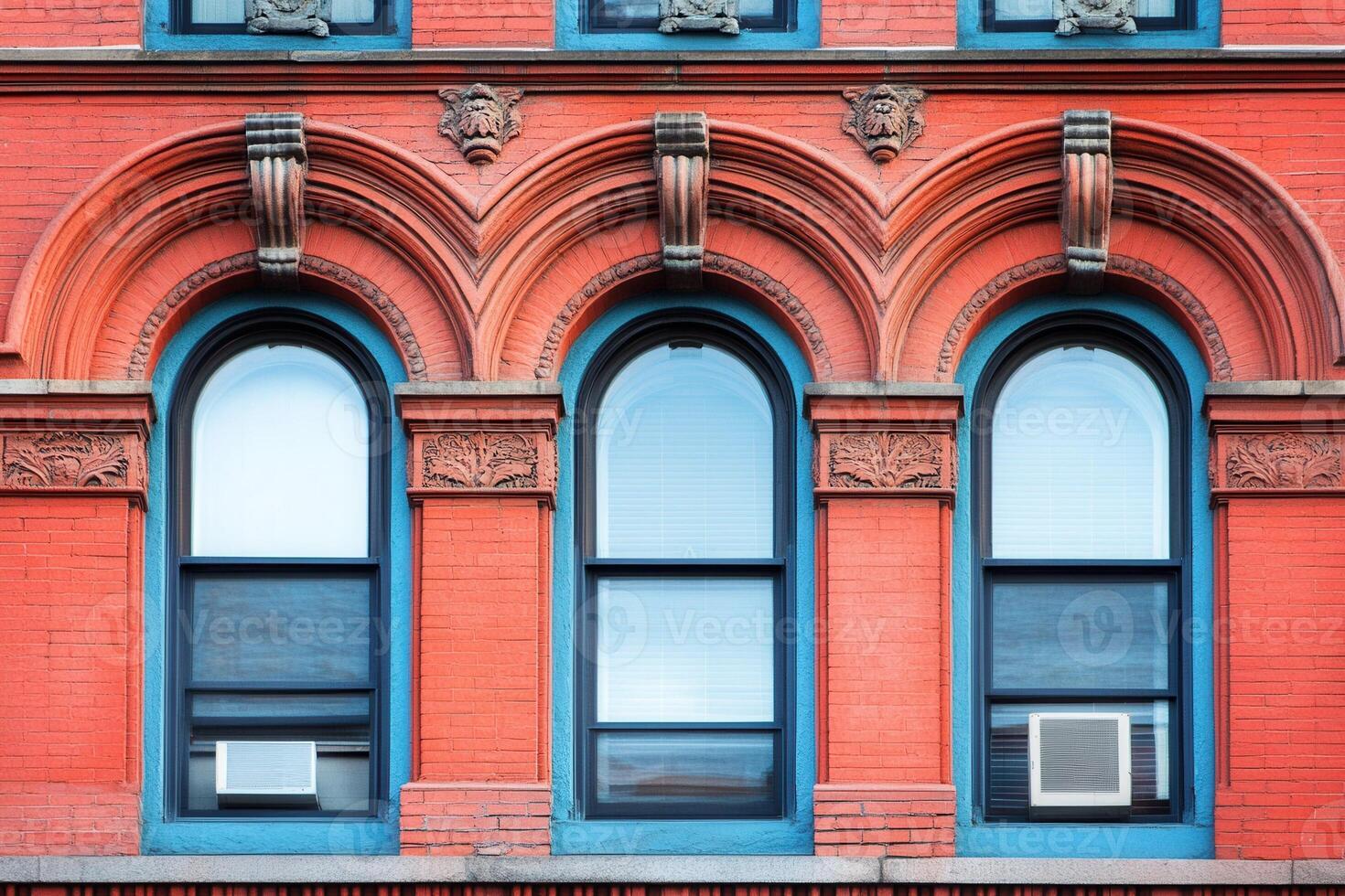 Three arched windows in a brick building with ornate trim. photo