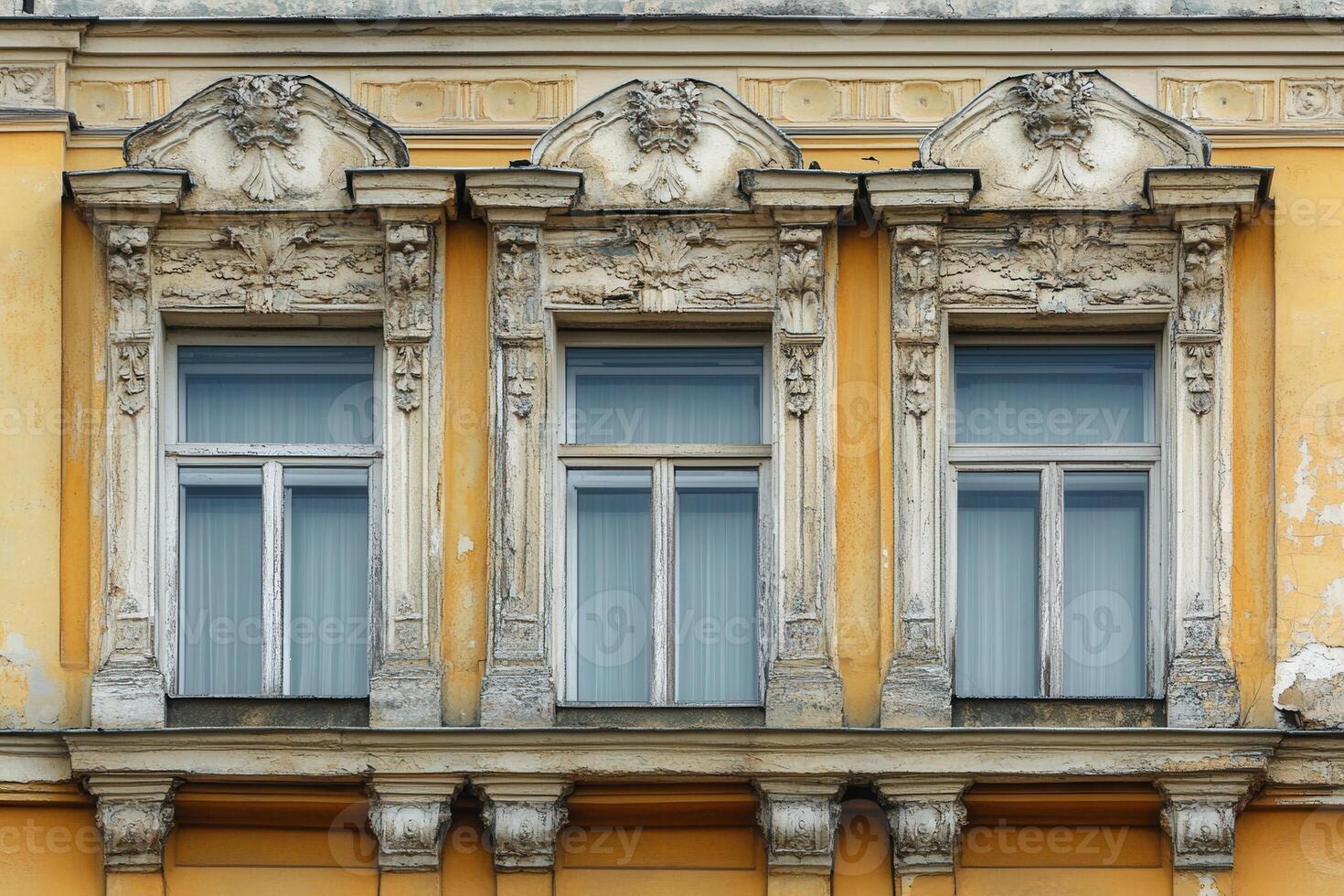 Three ornate windows on a yellow building facade. photo