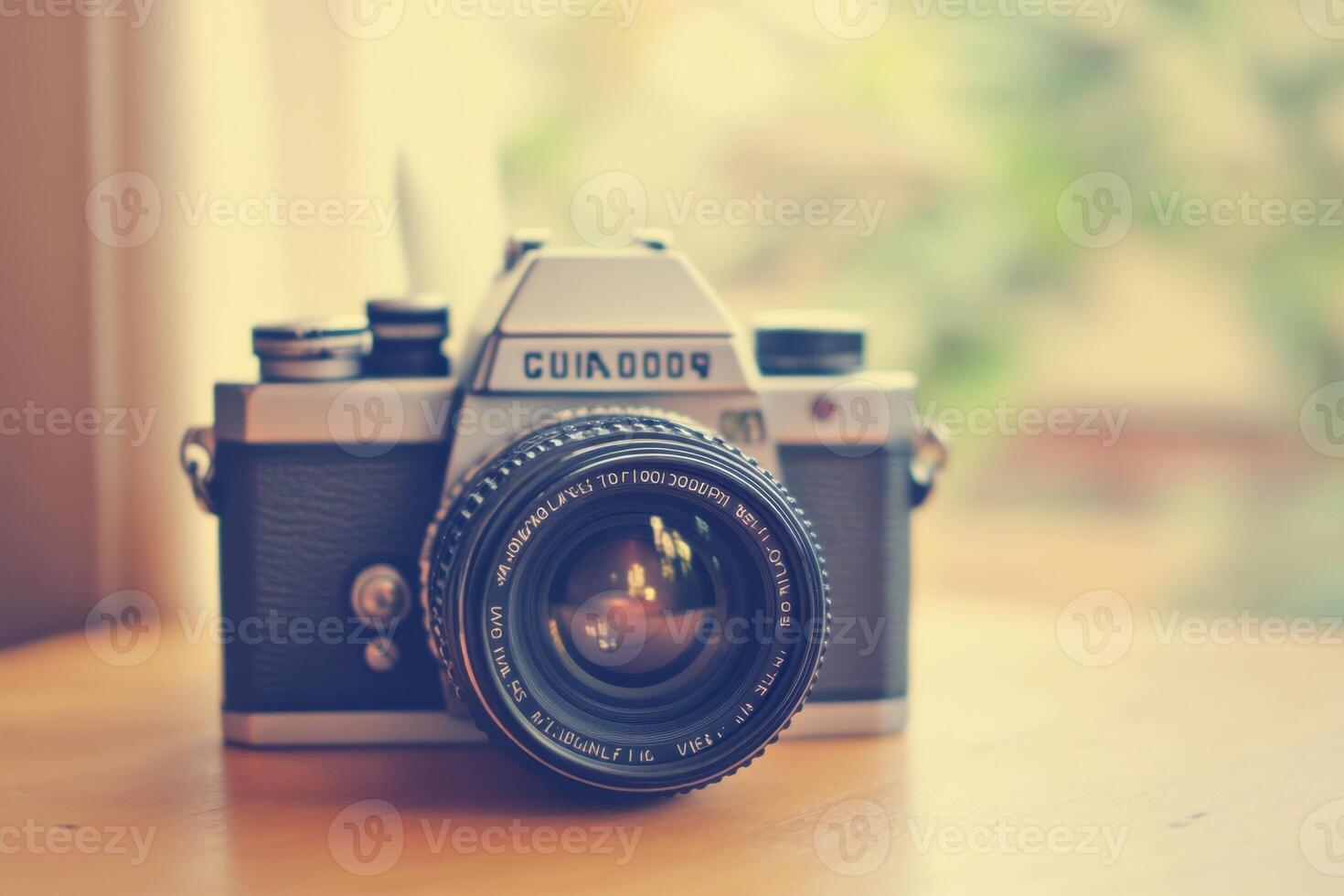 Vintage camera on a wooden table, with a blurry background of greenery. photo
