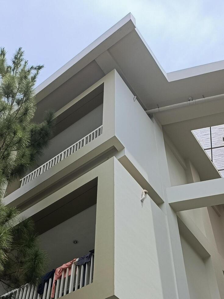 Modern Home Exterior with Balcony and Adjacent Pine Tree View photo
