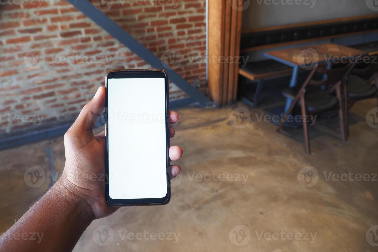 Individual Holding a Smartphone in a Contemporary Cafe Environment, Engaged and Relaxed photo