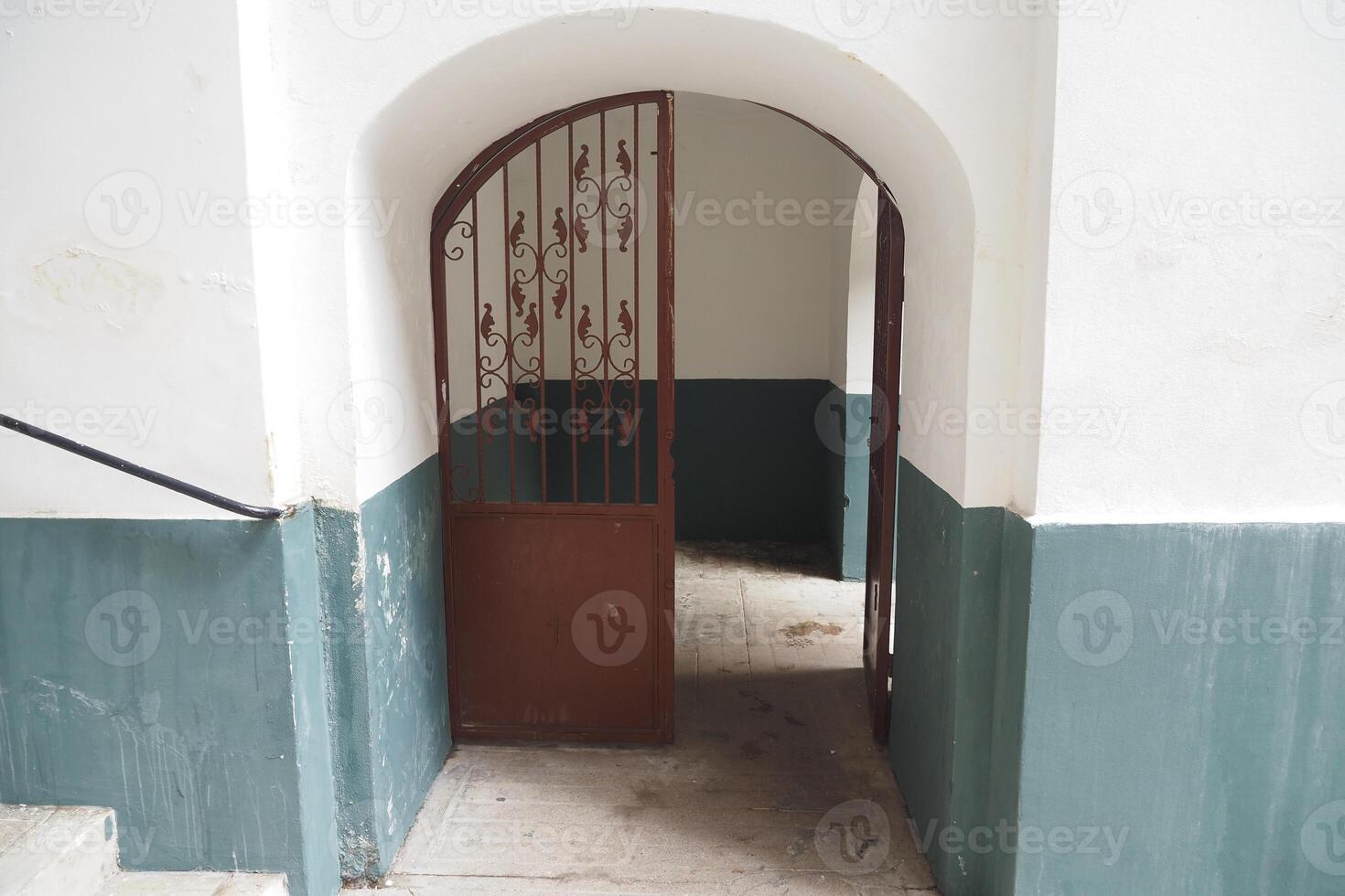 A Beautiful Rustic Archway Accompanied by an Intricate Iron Gate Located in an Old Stairwell photo