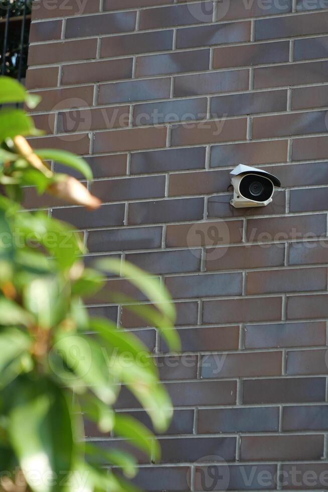 A visibly damaged security camera is mounted on a wall with its bracket still attached photo
