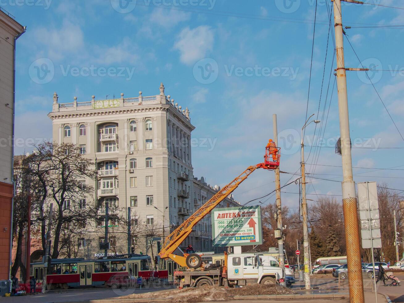 Electrician repairing wire of the power line with bucket hydraulic lifting platform on blue sky photo
