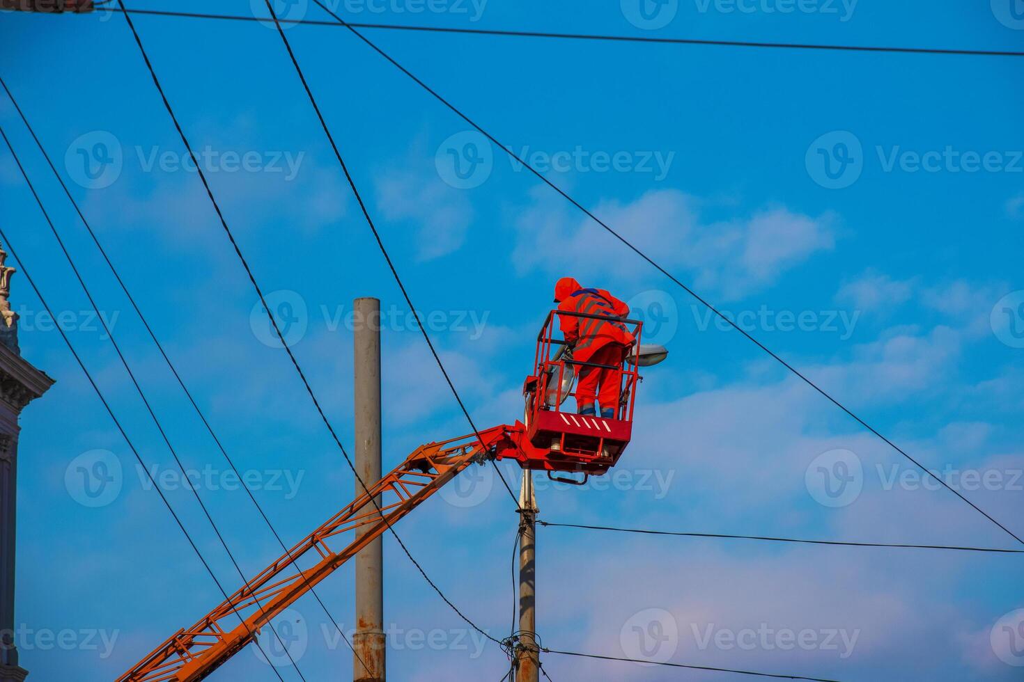 Electrician repairing wire of the power line with bucket hydraulic lifting platform on blue sky photo