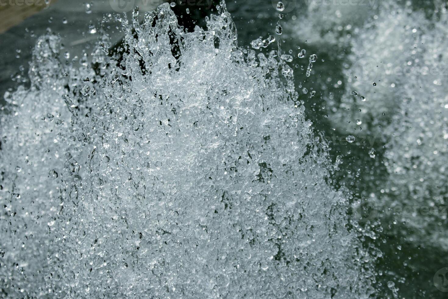 Close-up view of streams of fountain with reflection and lens flare. Water jet. City fountain. Water pressure. How to survive the heat. Splashes shining in the sun. Selective shallow focus. photo