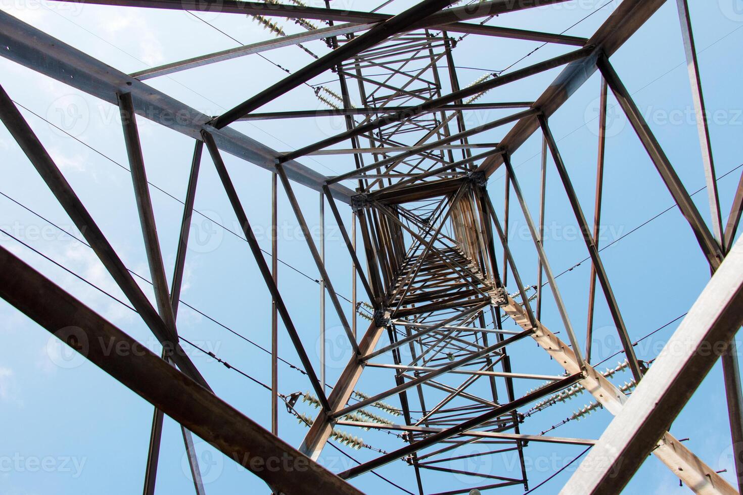 Close-up view of an electric tower with a beautiful blue sky background. Industrial engineering concept. Iron structure for high-voltage electrical engineering. photo
