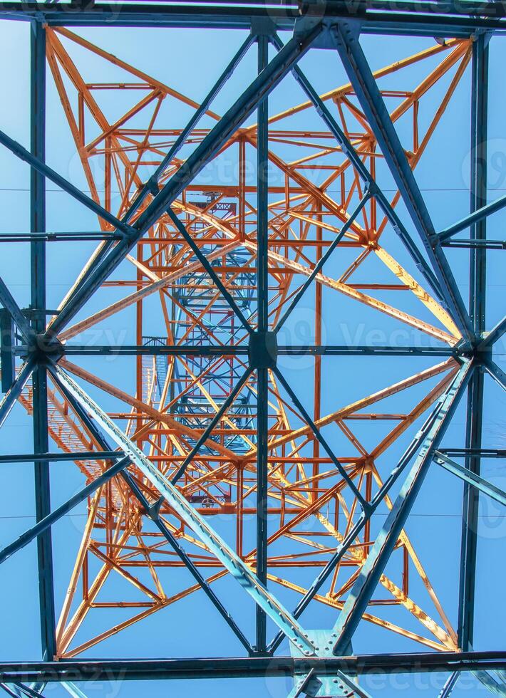 Close-up view of an electric tower with a beautiful blue sky background. Industrial engineering concept. Iron structure for high-voltage electrical engineering. photo