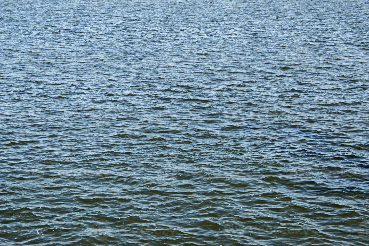 Calm water surface with small ripples. Background of the water surface of the river on a sunny day. photo