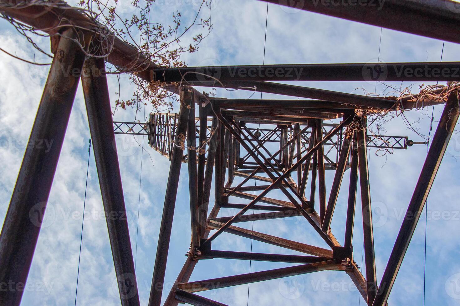 Close-up view of an electric tower with a beautiful blue sky background. Industrial engineering concept. Iron structure for high-voltage electrical engineering. photo