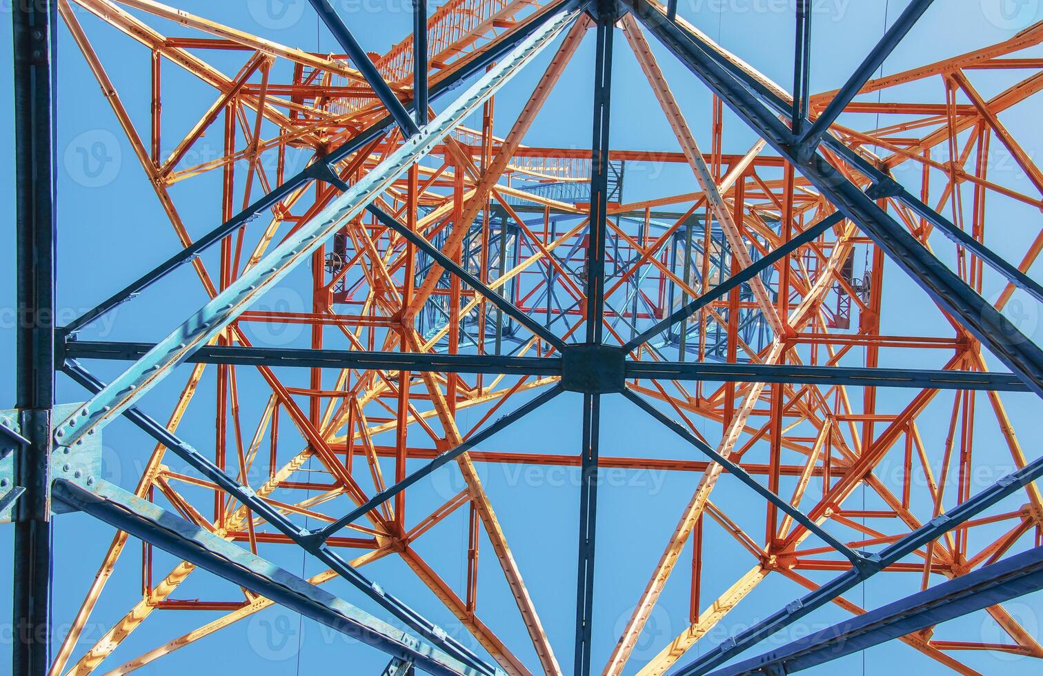 Close-up view of an electric tower with a beautiful blue sky background. Industrial engineering concept. Iron structure for high-voltage electrical engineering. photo