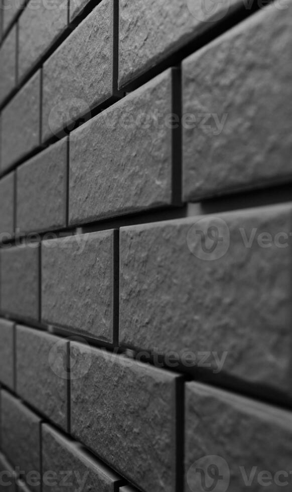 Wall tiles receding into the distance are arranged in even rows. Black and white vertical photo for wall pattern backgrounds