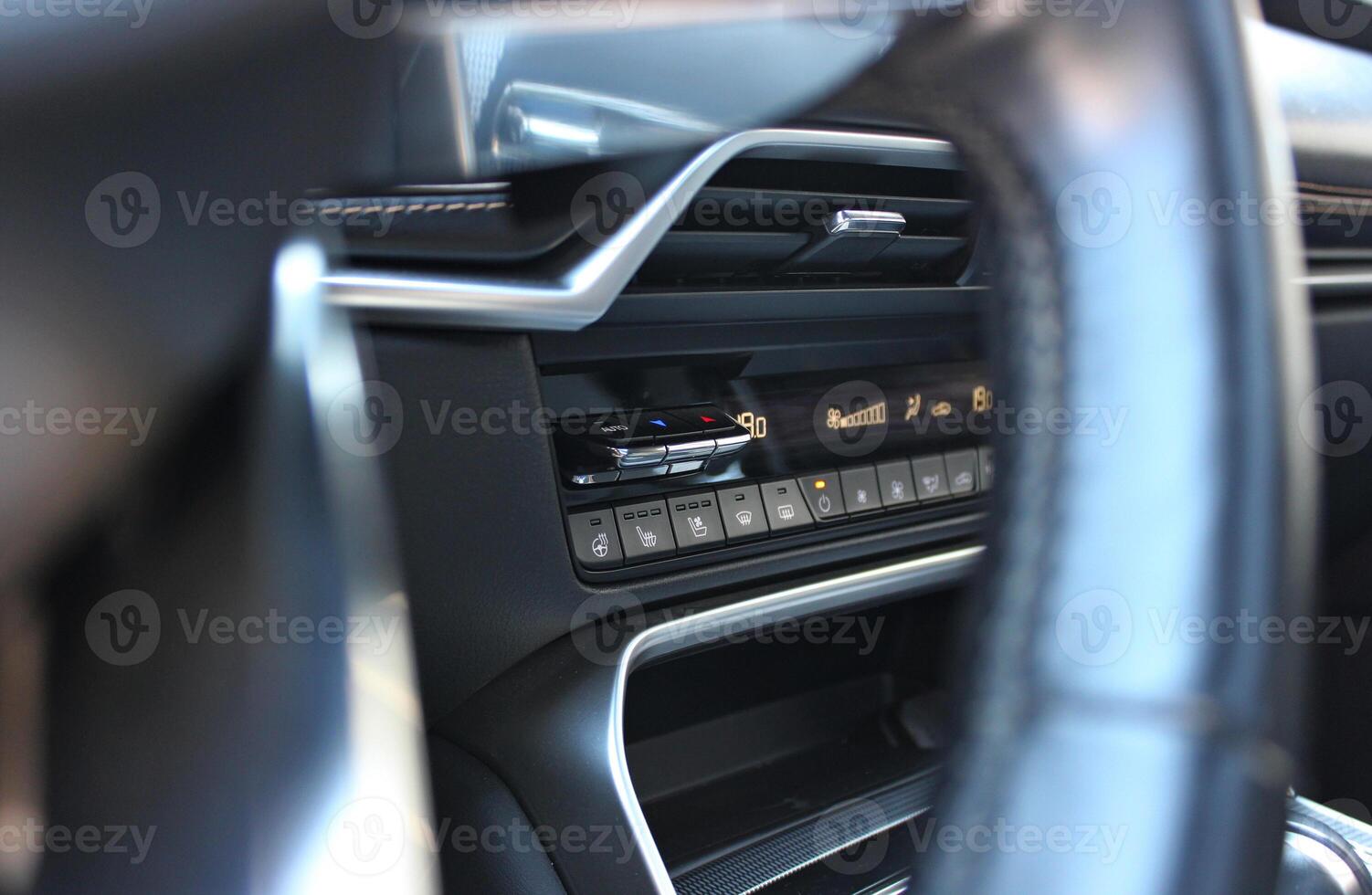 View of control panel and display of car climate system through the blurred steering wheel spokes photo