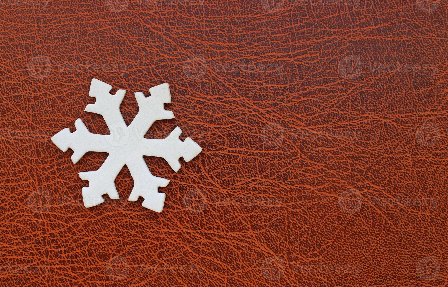 White Snowflake Model On Elegance Brown Leather Surface Copy Space Image. Snowflake Design For Greeting Card And Wallpaper Stock Photo