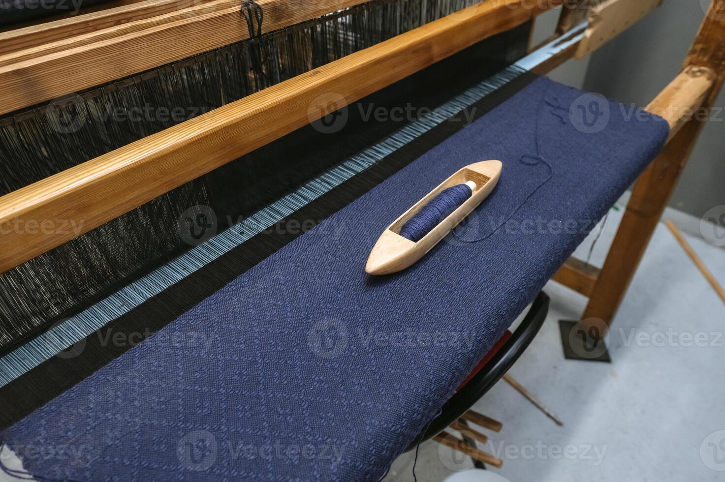 Traditional loom weaving with blue fabric and wooden shuttle for crafting and textile design photo