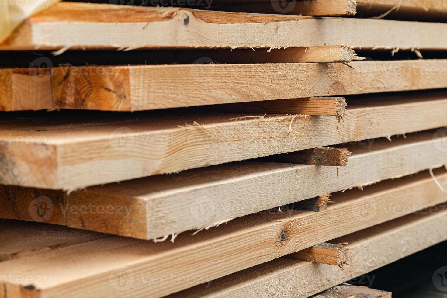 Stack of wooden boards. The boards appear rough-cut with visible knots and uneven edges. The wood been stacked for drying or storage. photo