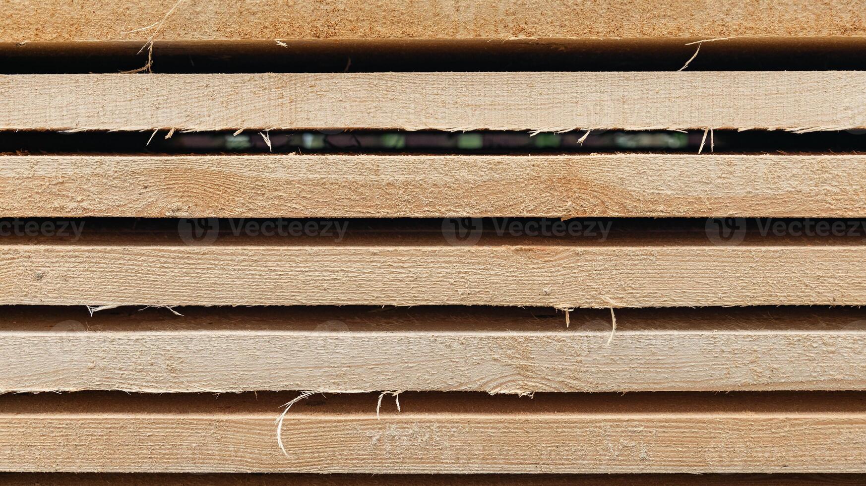 Stack of wooden boards. The boards appear rough-cut with visible knots and uneven edges. The wood been stacked for drying or storage. photo