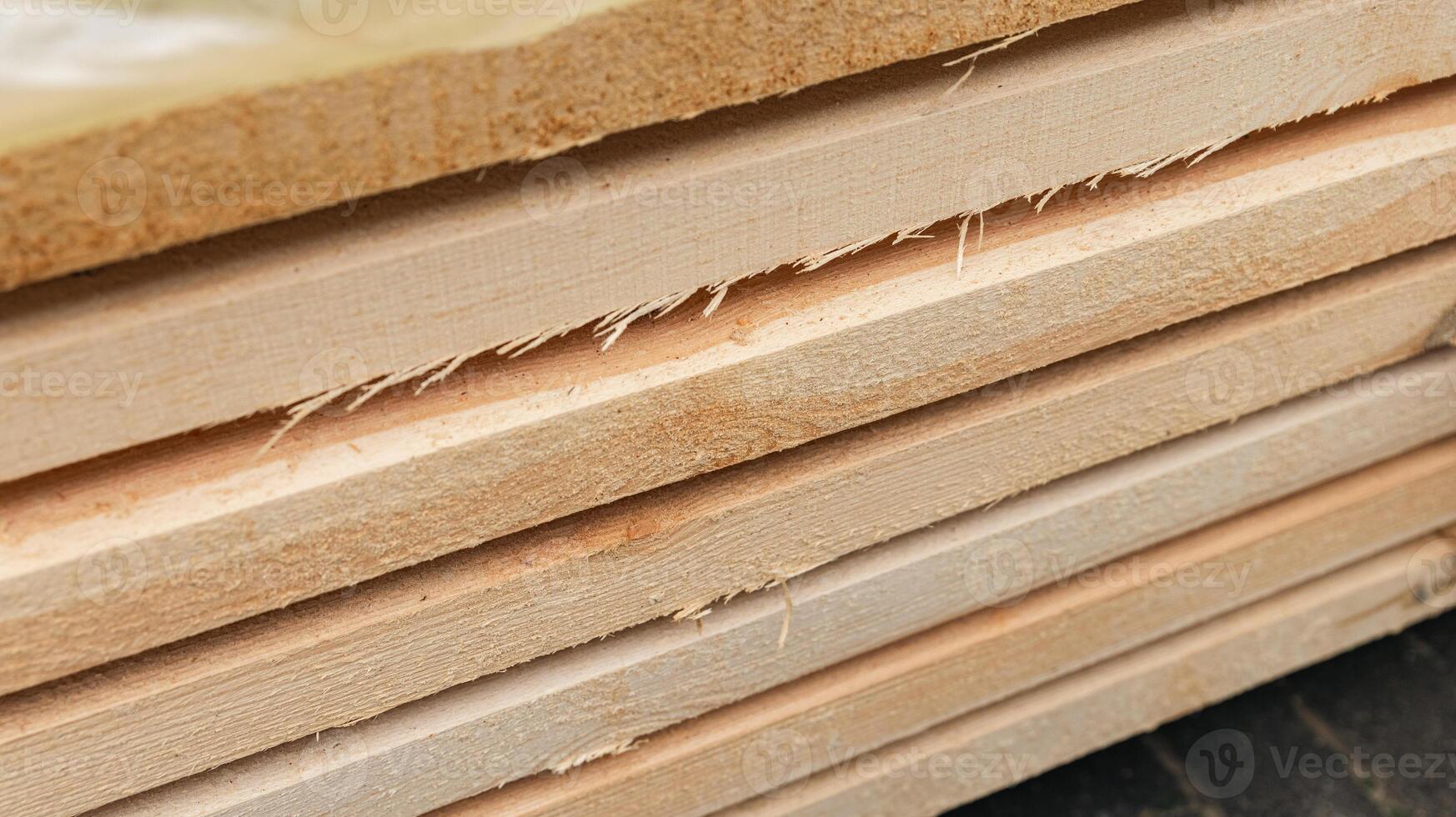 Stack of wooden boards. The boards appear rough-cut with visible knots and uneven edges. The wood been stacked for drying or storage. photo