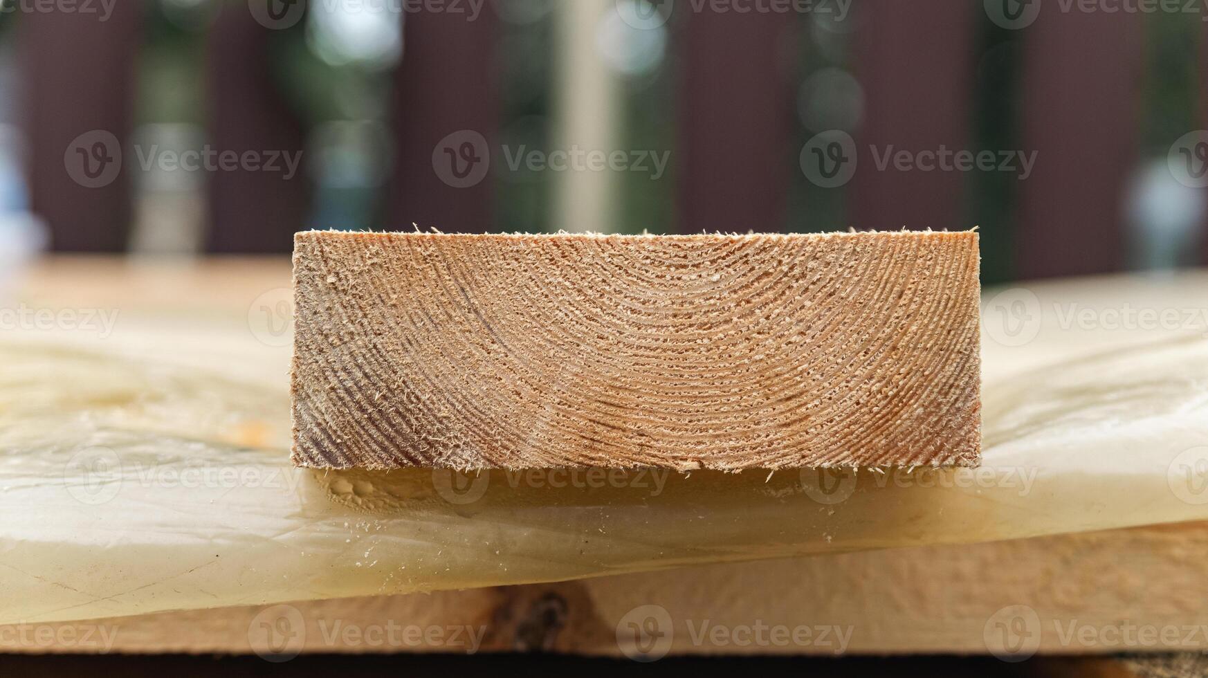 Stack of wooden boards. The boards appear rough-cut with visible knots and uneven edges. The wood been stacked for drying or storage. photo