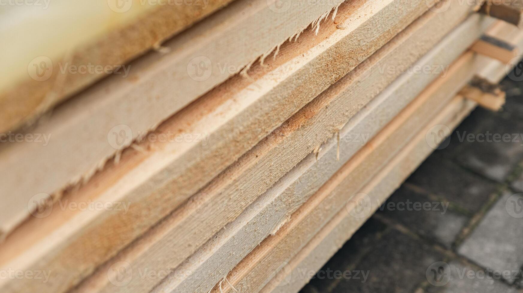 Stack of wooden boards. The boards appear rough-cut with visible knots and uneven edges. The wood been stacked for drying or storage. photo