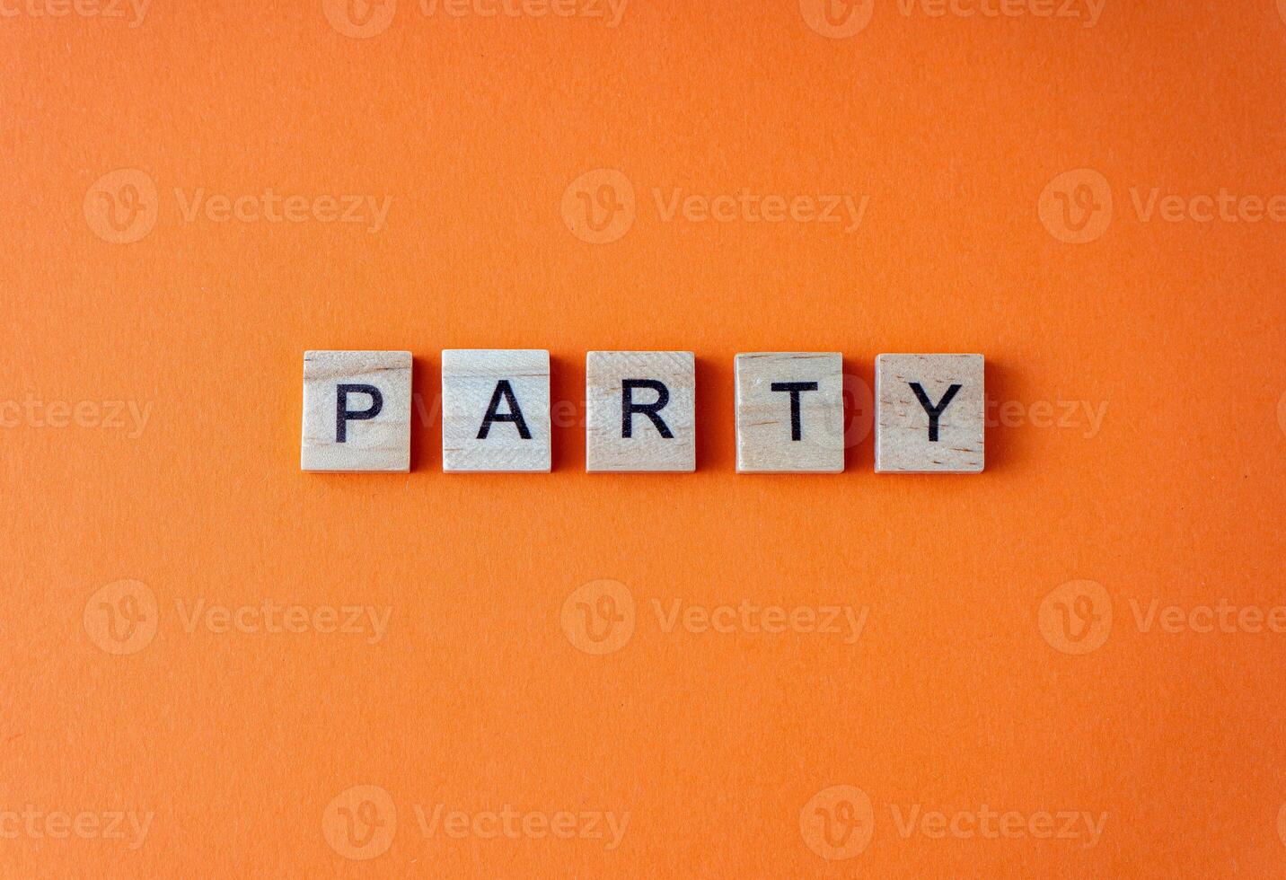 Party word. The phrase is laid out in wooden letters top view. Orange flat lay background. photo