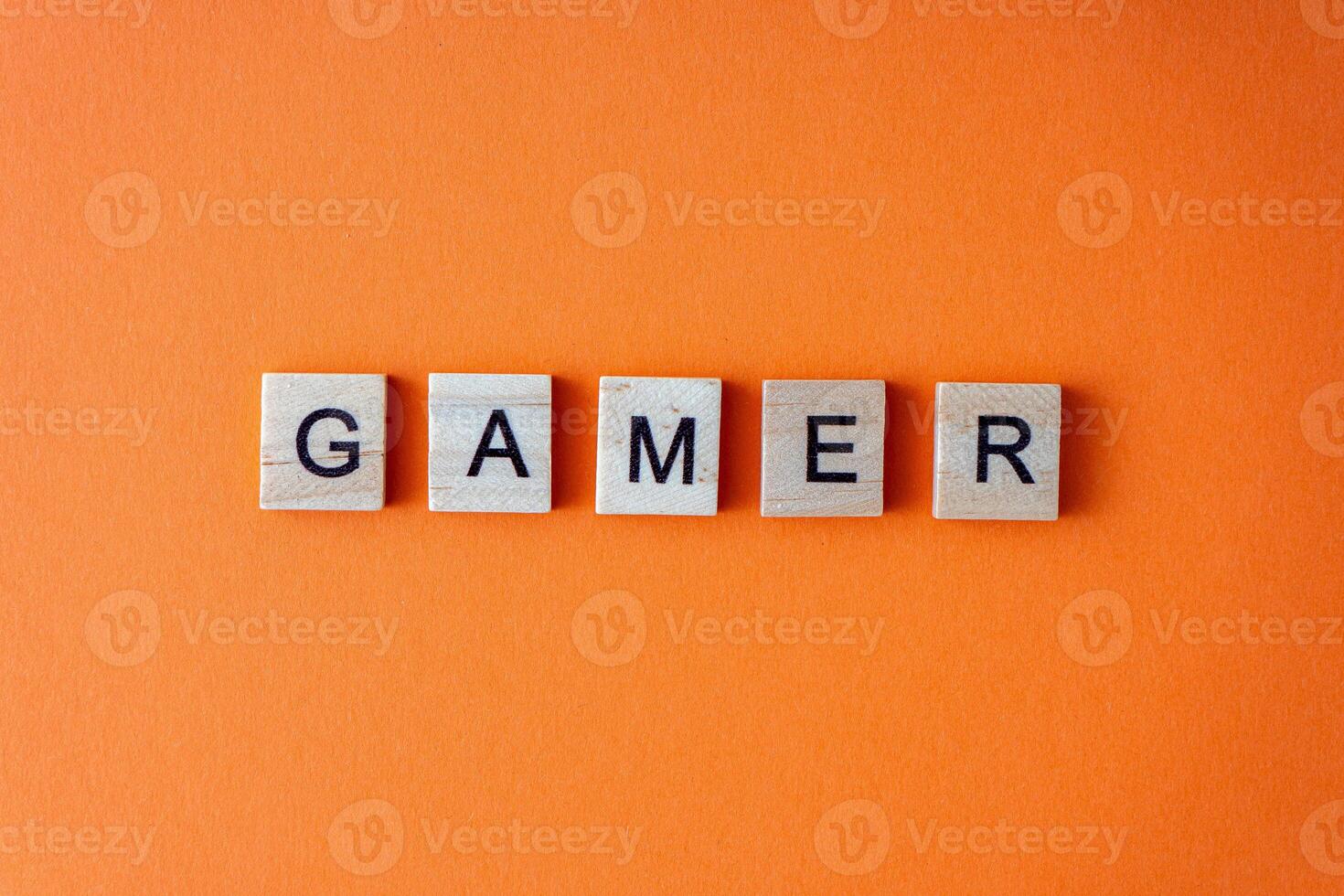 Gamer word. The phrase is laid out in wooden letters top view. Orange flat lay background. photo
