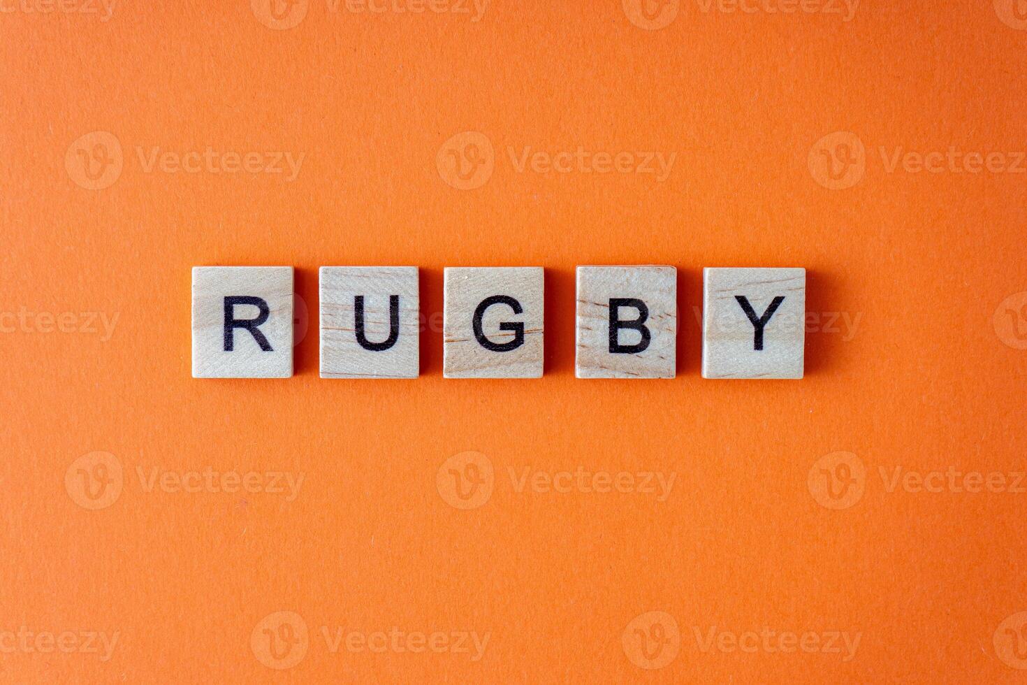 Rugby word. The phrase is laid out in wooden letters top view. Orange flat lay background. photo