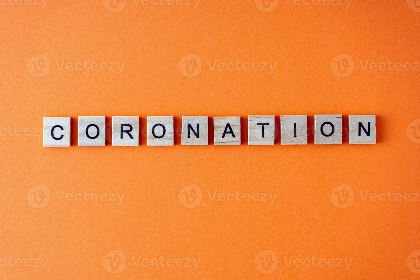 Coronation word. The phrase is laid out in wooden letters top view. Orange flat lay background. photo
