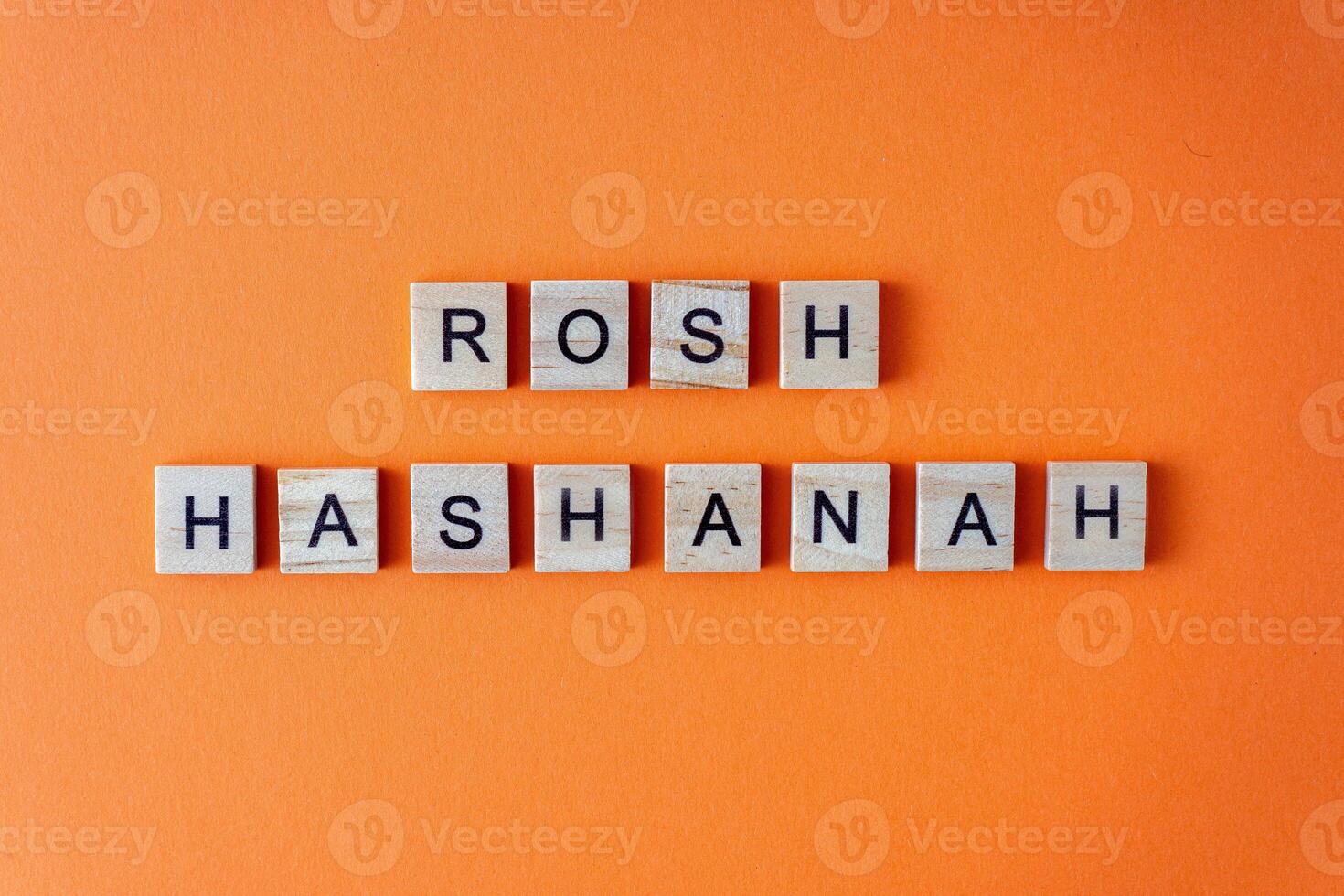 Rosh Hashanah word. The phrase is laid out in wooden letters top view. Orange flat lay background. photo
