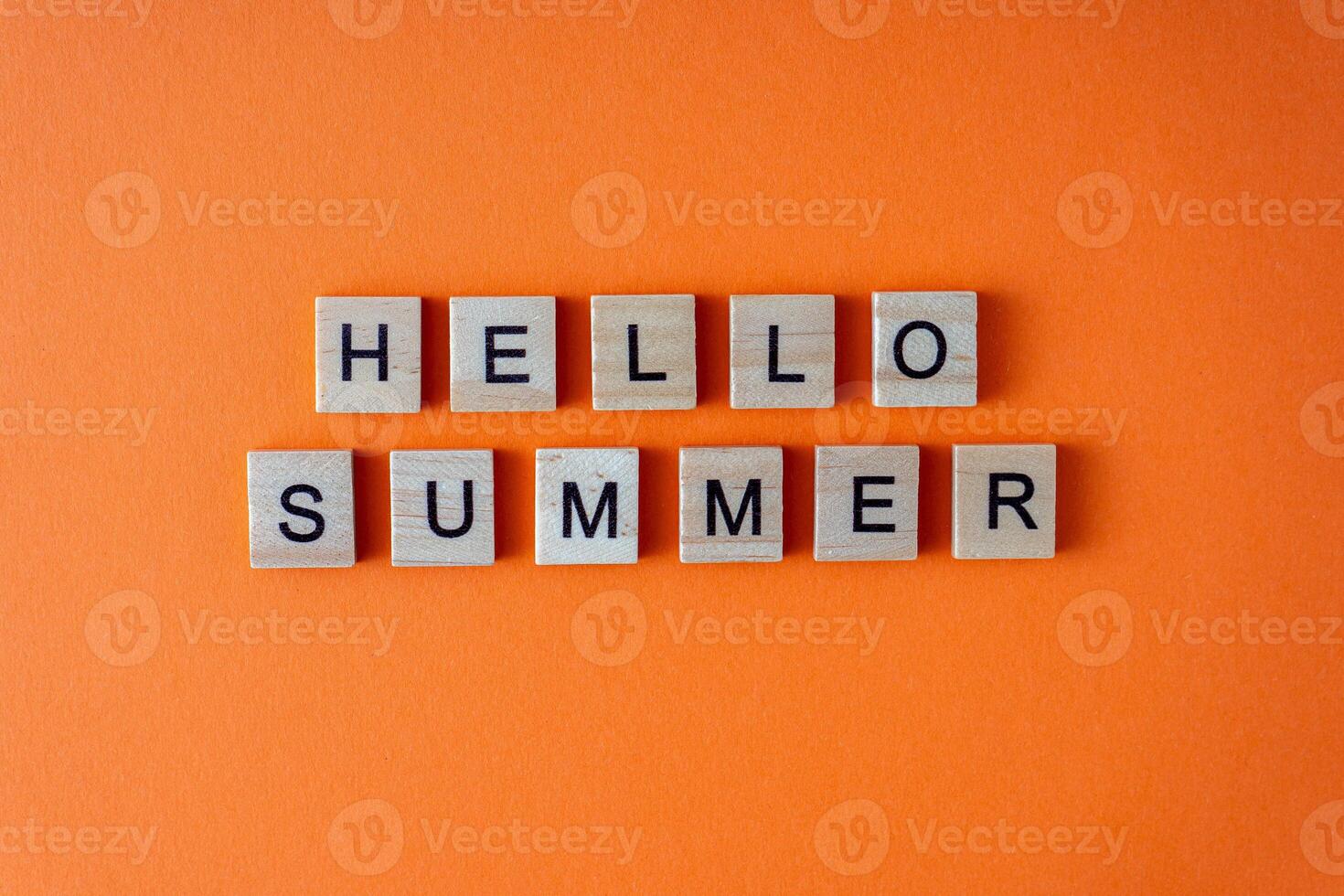 Hello summer word. The phrase is laid out in wooden letters top view. Motivation. Orange flat lay background. photo