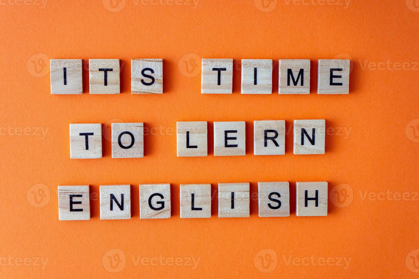 Word It is time to learn English. Motivation. The phrase is laid out in wooden letters top view. Motivation. Orange flat lay background. photo
