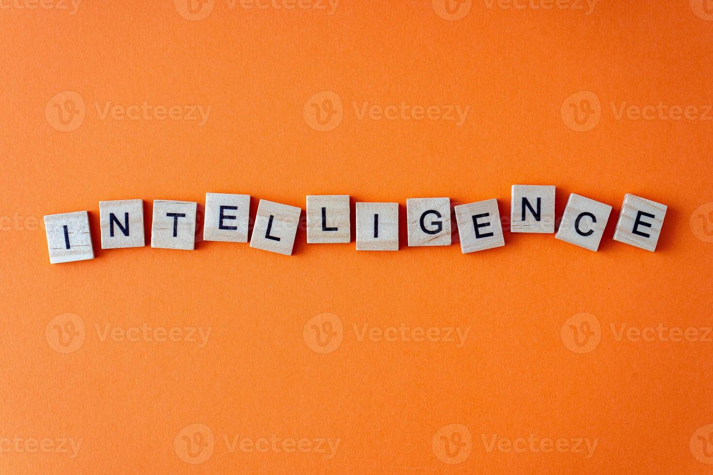 Word intelligence. The phrase is laid out in wooden letters top view. Orange flat lay background. photo