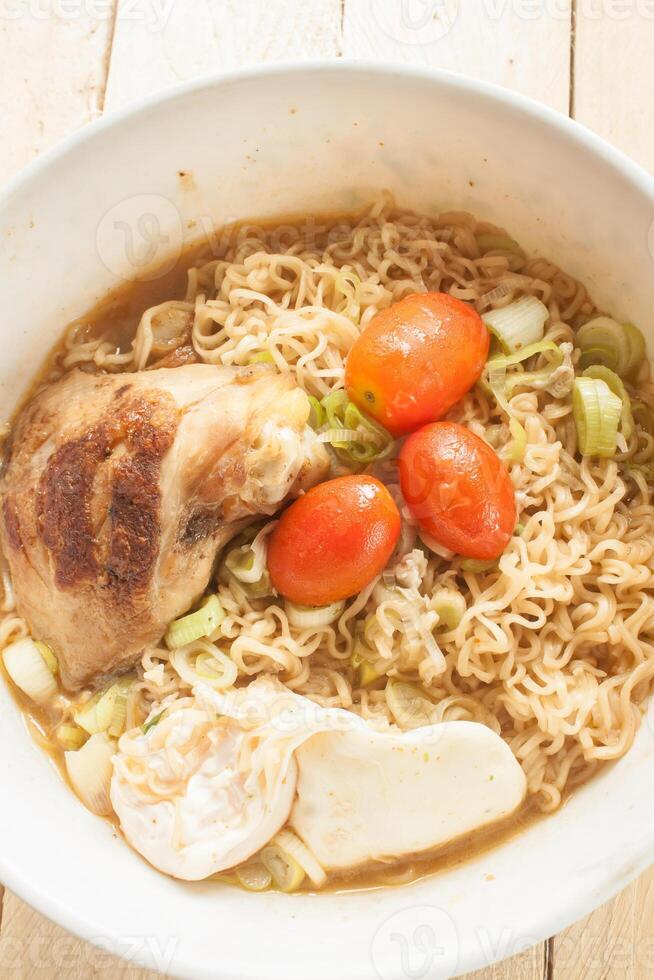 Instant noodlesGrilled Chickenboiled eggonion Pork soupIn a white cupPlaced on the wooden floor photo