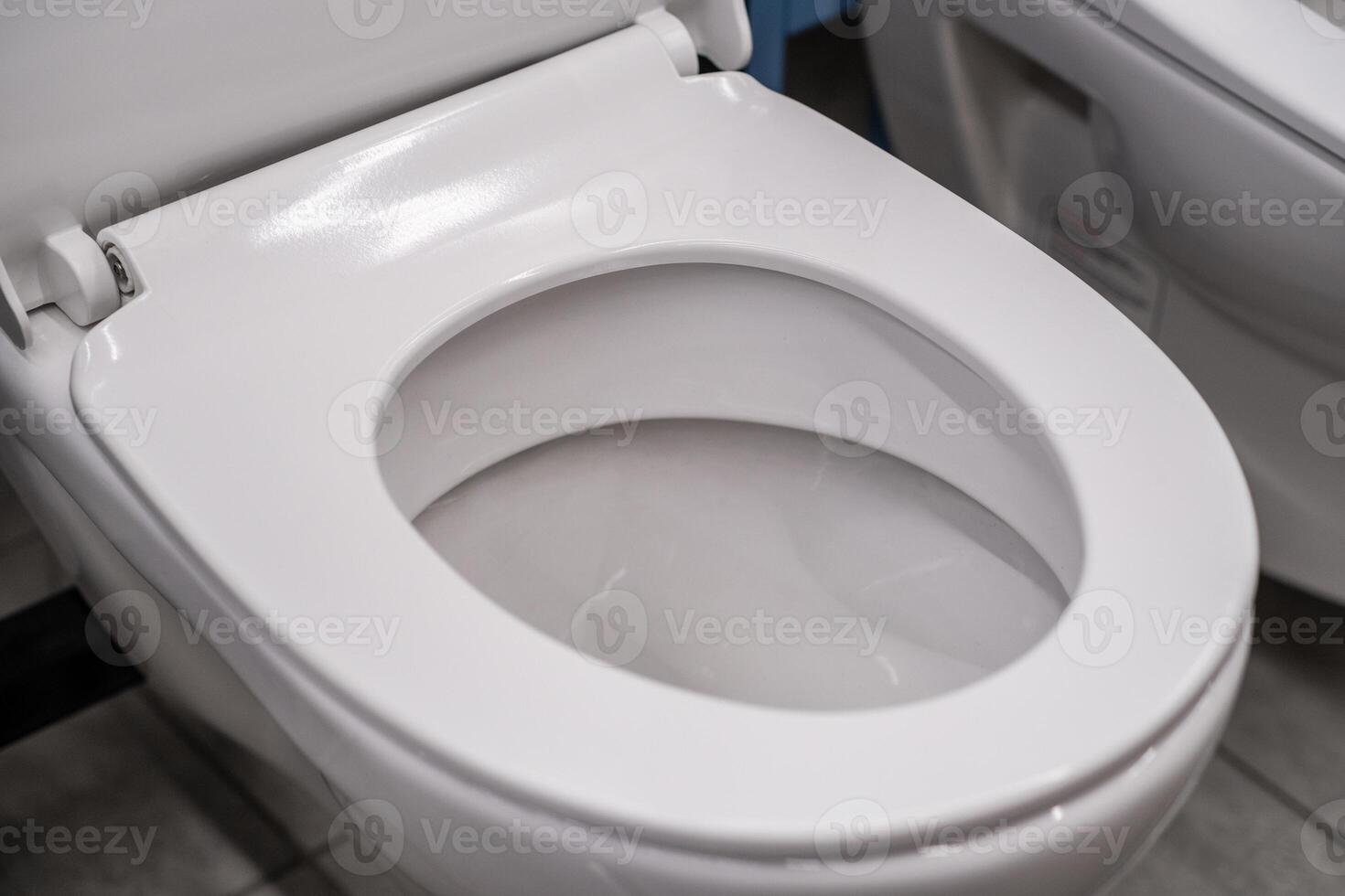 Closeup of an empty toilet in a bathroom with ceramic seat and rectangle shape photo