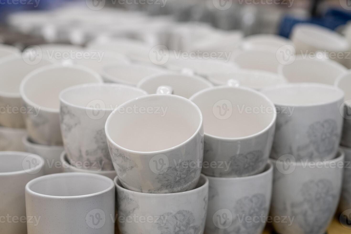 A stack of white mugs and plates in the store for sale. White and clean dishes photo