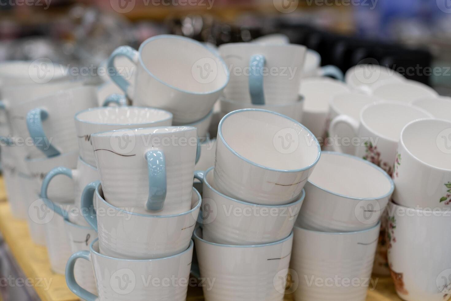 A stack of white mugs and plates in the store for sale. White and clean dishes photo