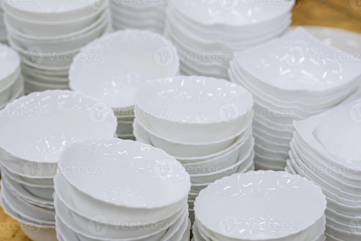 A stack of white mugs and plates in the store for sale. White and clean dishes photo